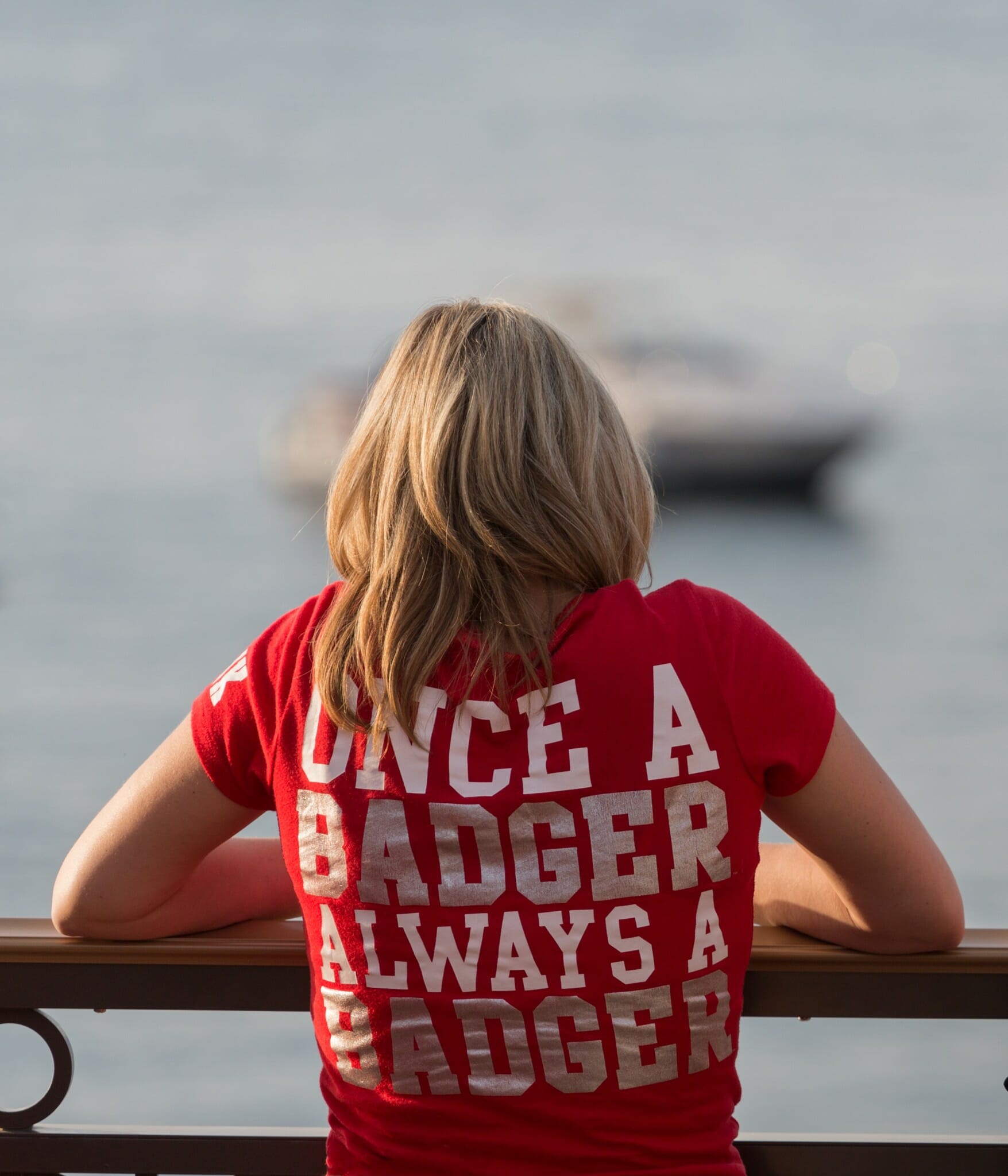 Woman looking out at water with shirt that says, "Once a Badger Always a Badger"