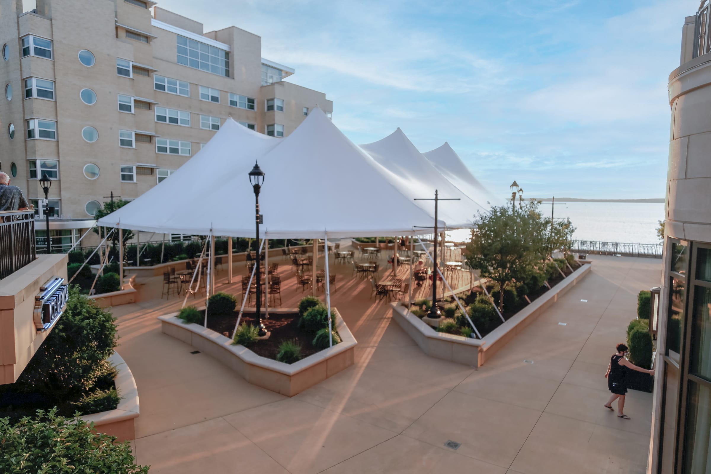 Dining tables and chairs set up under a tent on the grand plaza